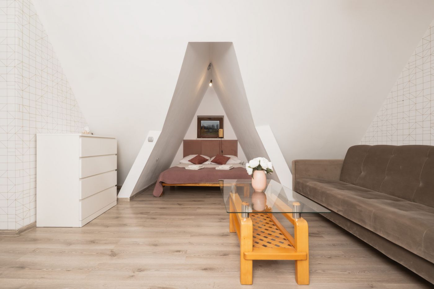 Apartament — sypialnia poddasza w trójkątnej niszy z drewnianym łóżkiem